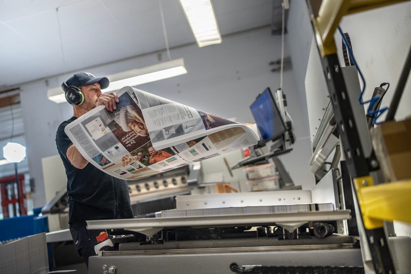 produktion-og-efterbehandling-af-tryksager.jpg Medarbejder efterbehandler trykte materialer i produktionen