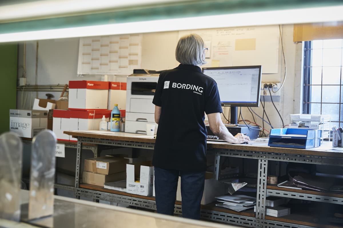 Bording-medarbejder behandler og koordinerer lagerordrer ved en computer.